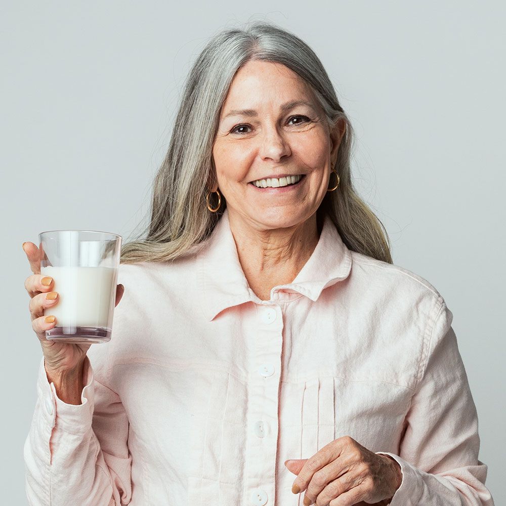 cheerful senior woman drinking a glass of milk JCZ5NPQ